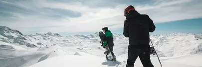 snowboardeurs qui marchent au sommet d'une montagne dans la poudreuse