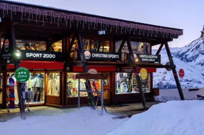 Gevel van de winkel Sport 2000 Christina Sports in Arc 1600, verlichte etalages in de sneeuw bij schemering